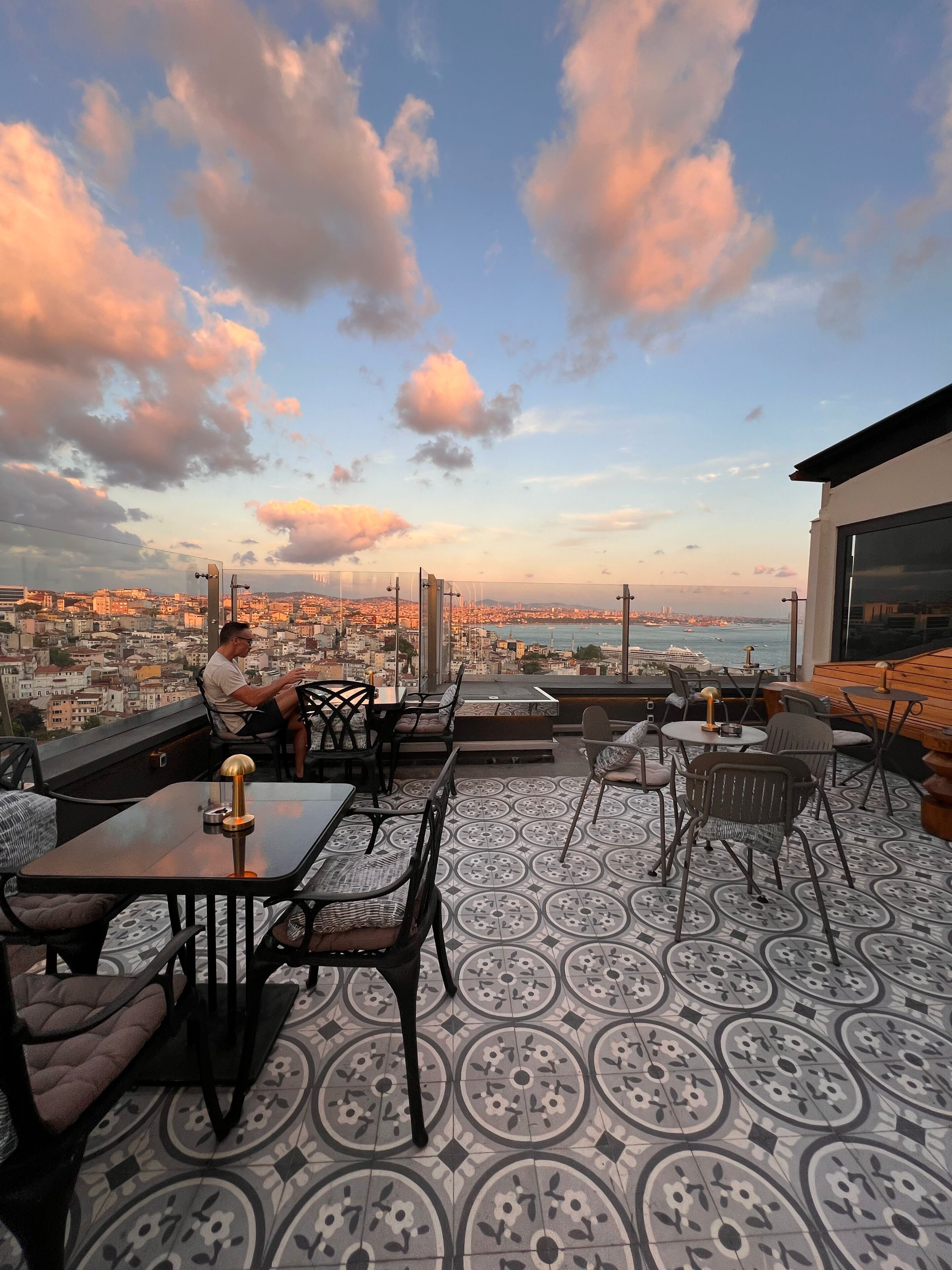 Terraço no telhado com área de estar ao ar livre, vista da cidade e piso estampado.