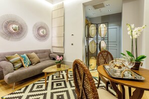 A modern living room with a sofa, coffee table, dining table, chairs, decorative mirrors, and a patterned rug. - Ravouna 1906 Suites - Special Class, Adults Only (Istanbul)