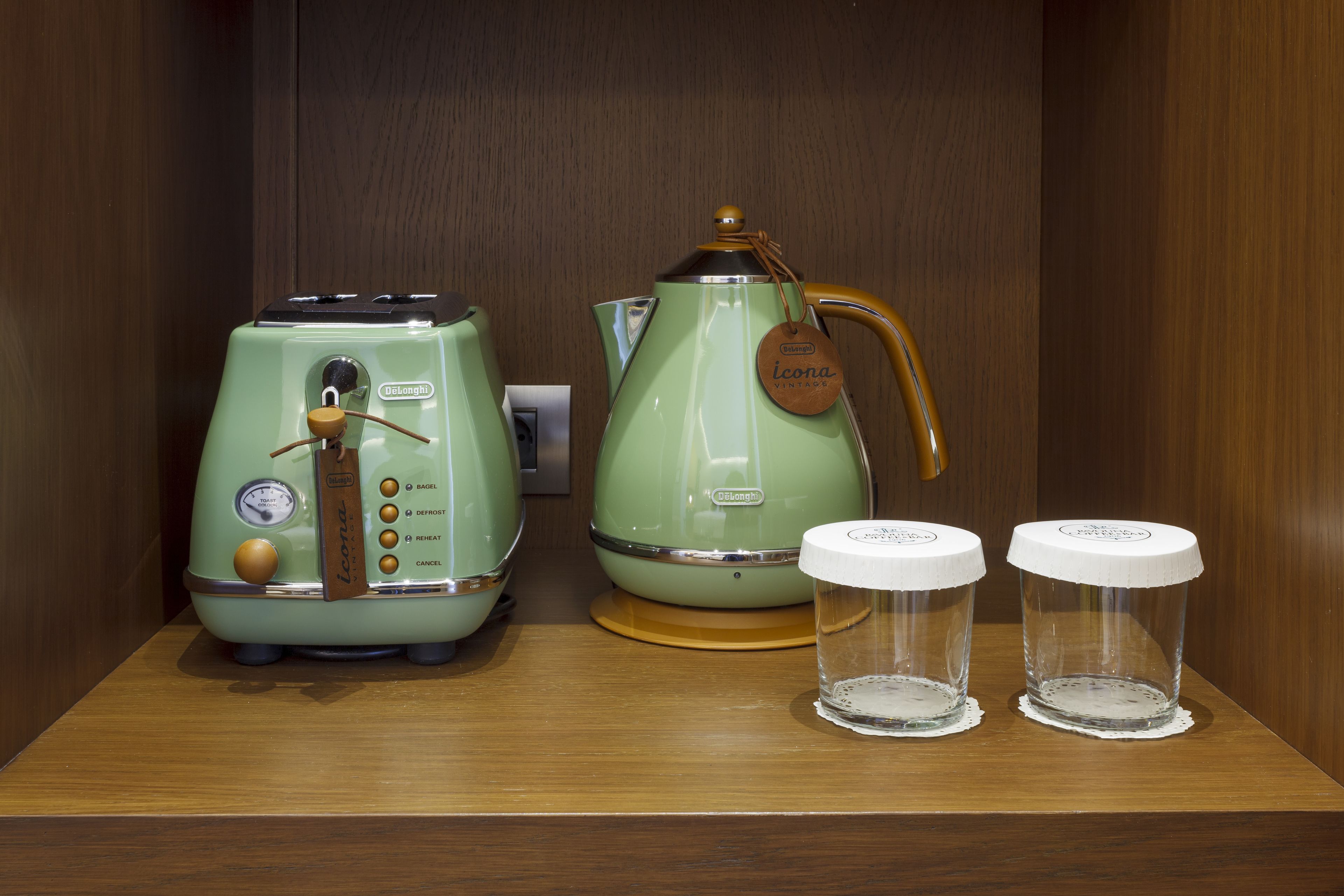 A kitchen area with vintage green appliances, including a toaster and a coffee maker, and two glass containers on a wooden countertop.