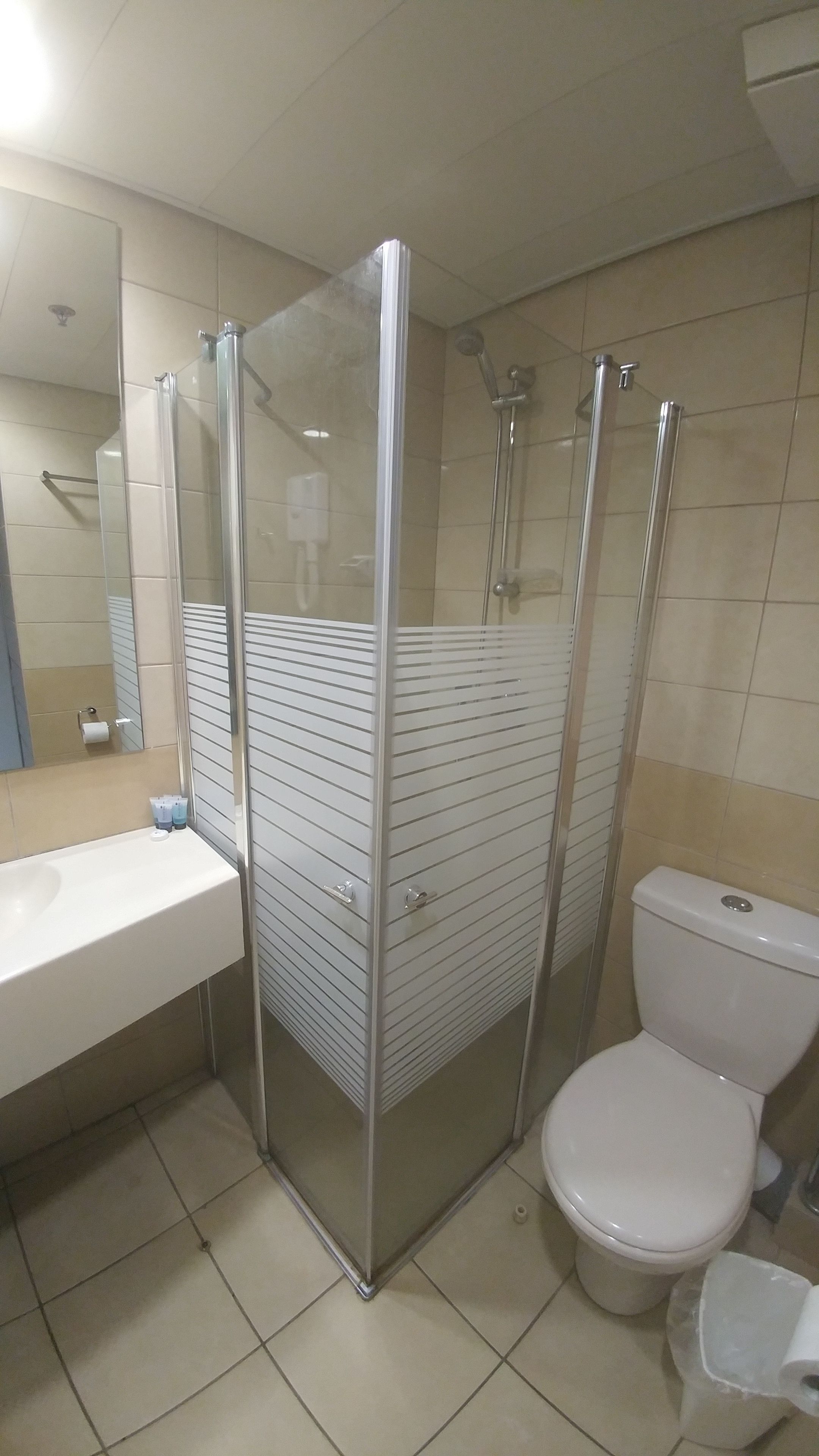 A bathroom with a glass-enclosed shower, a toilet, and a sink.