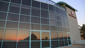 Un bâtiment moderne aux grandes fenêtres en verre qui reflètent le coucher de soleil.