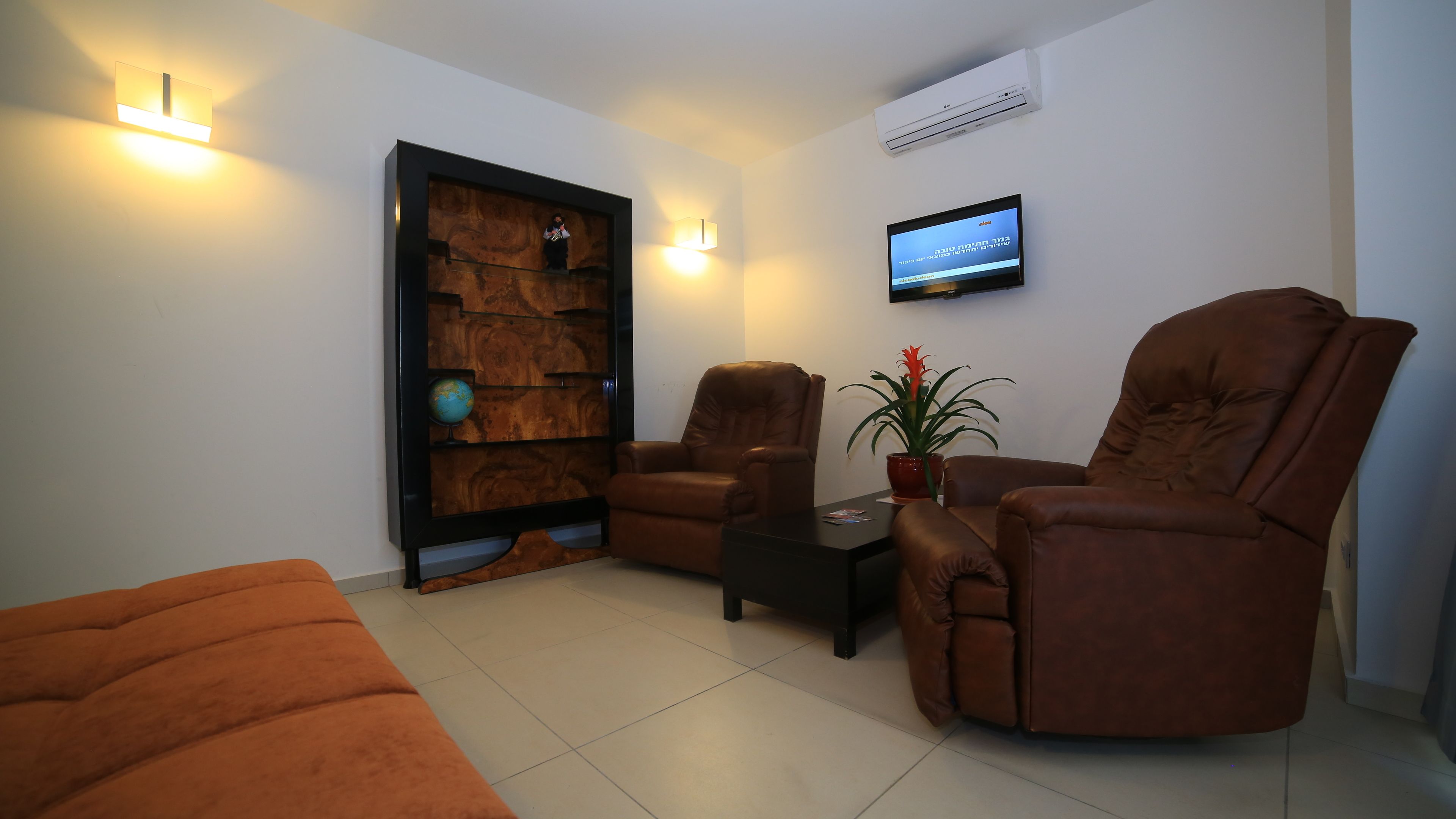 Una sala de estar moderna con dos sillones de cuero, una mesita de centro y un televisor montado en la pared.