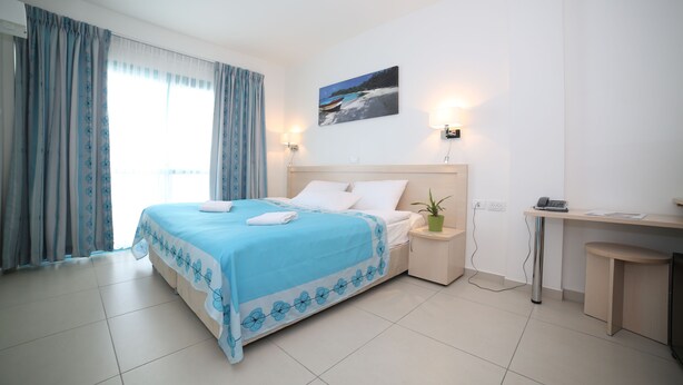 Une chambre d’hôtel bien rangée, avec un lit, une table de chevet et un bureau.