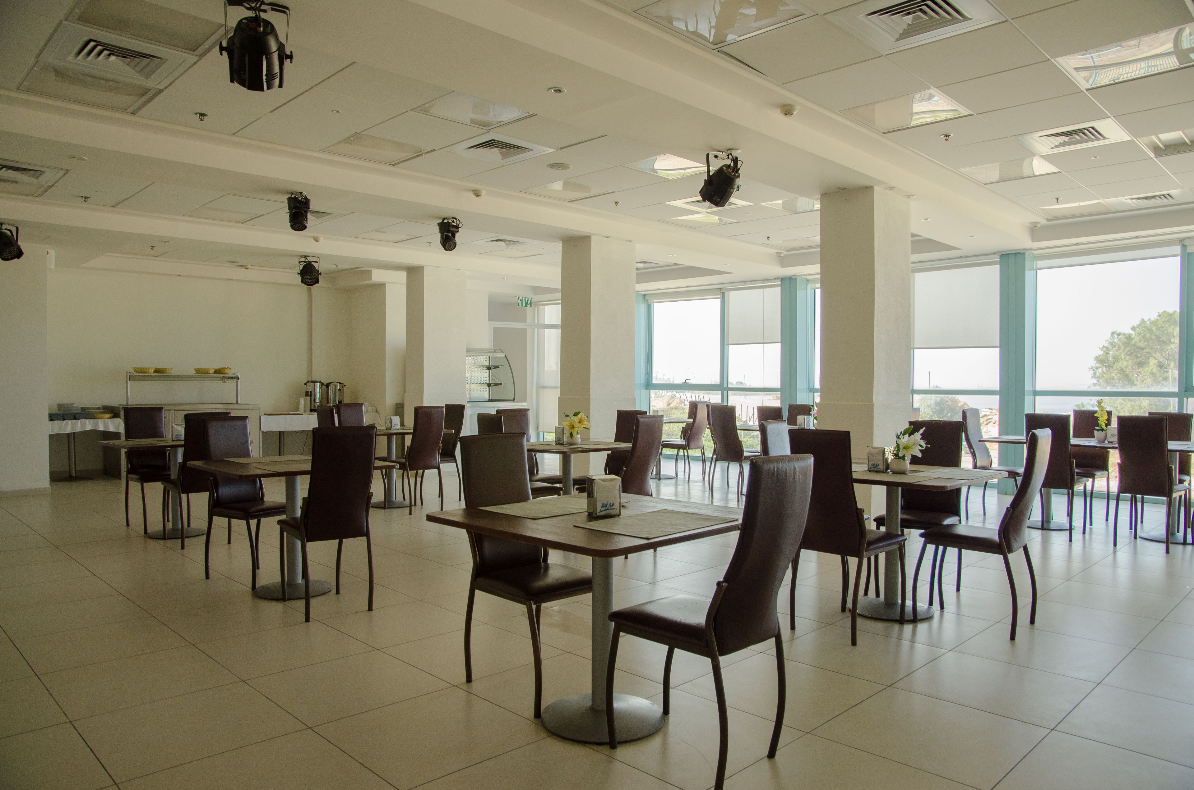 Un comedor amplio con varias mesas y sillas, ventanas grandes y un interior moderno y cuidado.