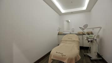 A spa room with a bed, a mirror, a sink, and a medical device.