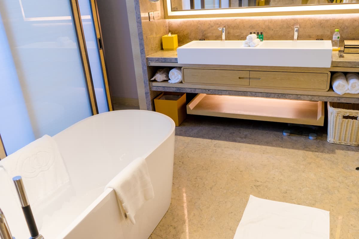 Un baño moderno con una bañera independiente, un espejo grande y un mueble de tocador con lavabo y espacio para toallas.