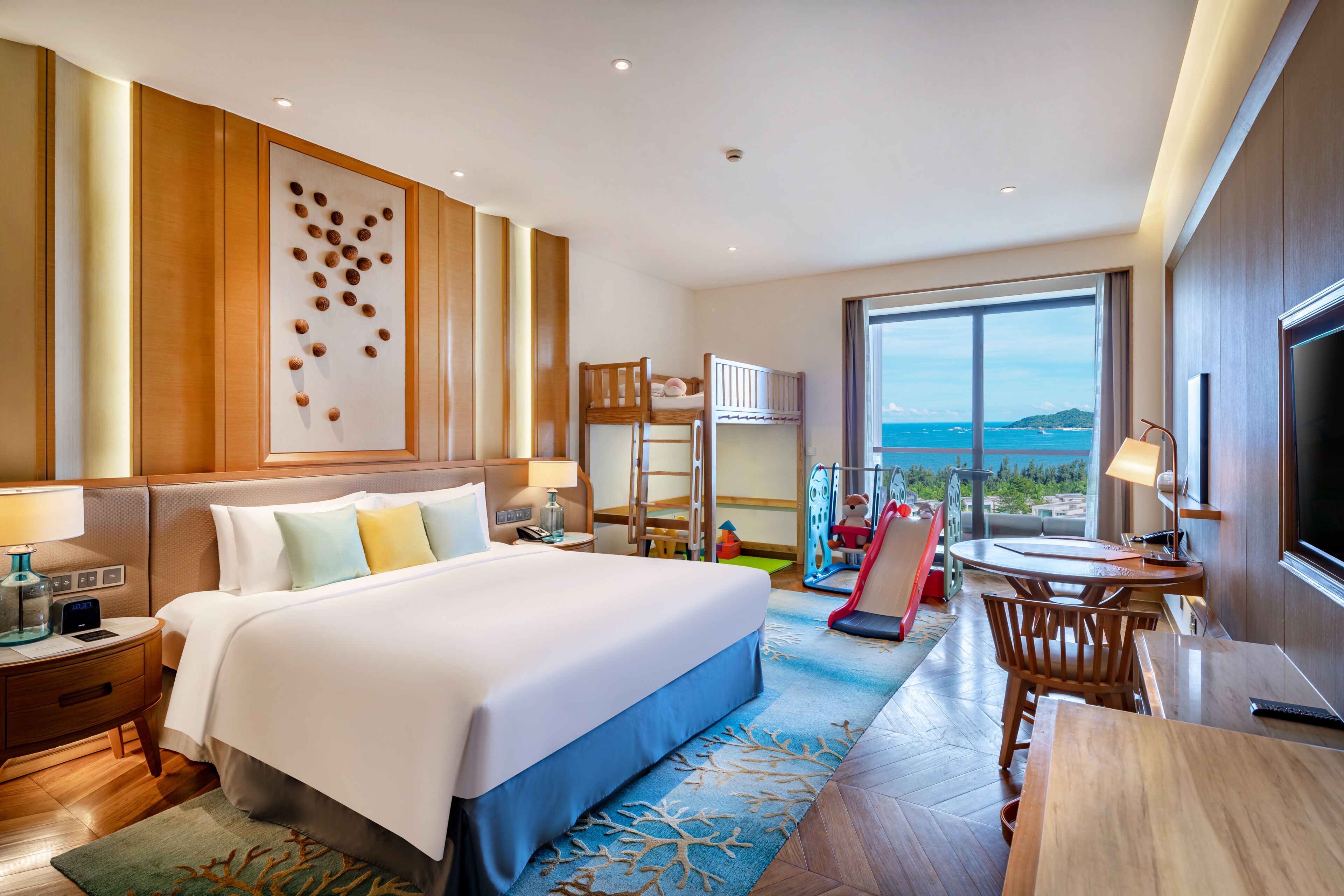 A hotel room with a large bed, a desk, a TV, and a balcony with a view.