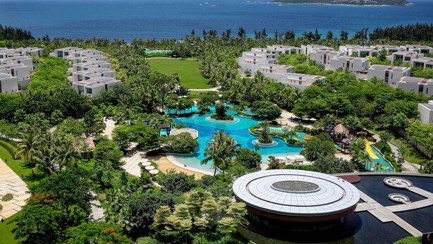 Um resort com villas modernas, uma piscina central e vista para o mar.