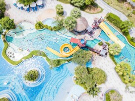 Vista aérea de un parque acuático con múltiples piscinas, toboganes y una zona de juegos central.