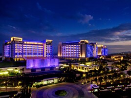Un hotel grande con varias edificaciones, un atrio central y una zona ajardinada con una entrada circular.