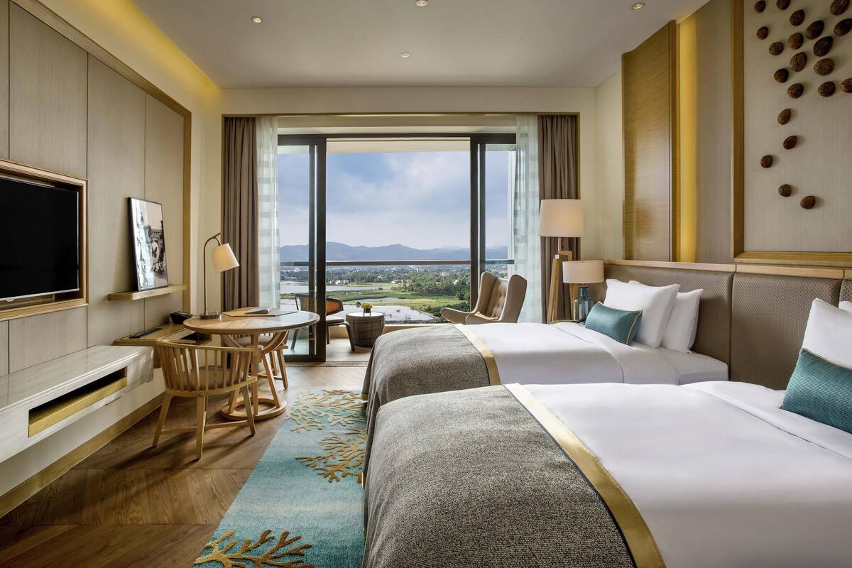 Ein Hotelzimmer mit Bett, Schreibtisch, Fernseher und Blick auf die Landschaft.