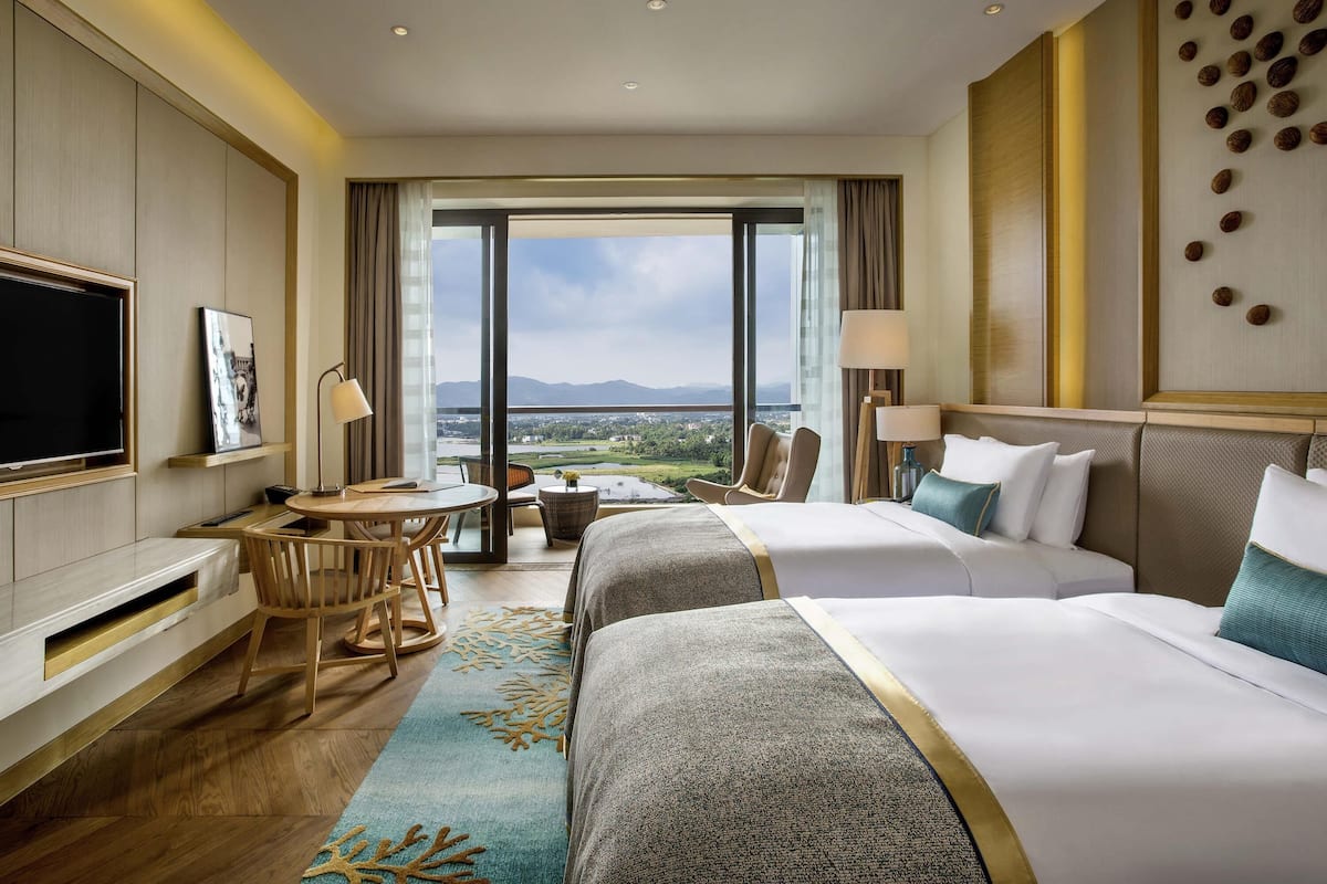 Ein Hotelzimmer mit Bett, Schreibtisch, Fernseher und Blick auf die Landschaft.
