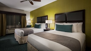 A hotel room with two beds, a ceiling fan, a TV, and a window with curtains.
