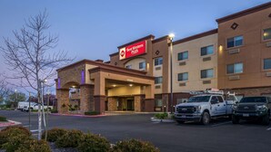 A Best Western Plus hotel with a brick facade, a covered entrance, and a parking lot with two service trucks.