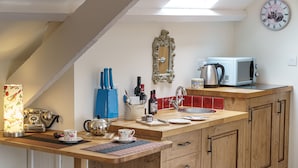 Une cuisine avec un plan de travail en bois, un évier, un four à micro-ondes et une horloge au mur.