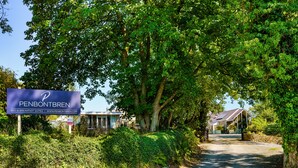 Une enseigne pour le Penbontbren Bed & Breakfast Suites, avec un mur en pierre et de la verdure.