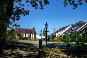 Una calle residencial con casas, un muro de piedra y un farol.