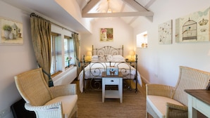 Une chambre à coucher avec un lit, deux chaises, une petite table et des œuvres d’art accrochées aux murs.