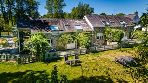 Un bâtiment en pierre comprenant plusieurs pièces, une cour clôturée et des espaces de repos extérieurs.
