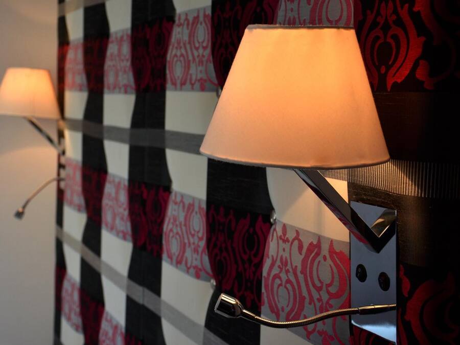 Two wall-mounted lamps with adjustable arms in a room with patterned wallpaper.
