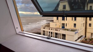 A view from a window overlooking a beach with buildings in the background.