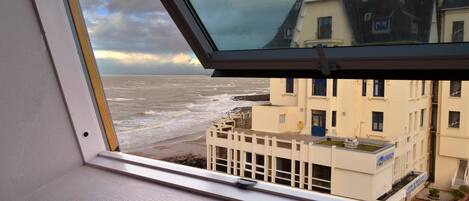 A view from a window overlooking a beach with buildings in the background.