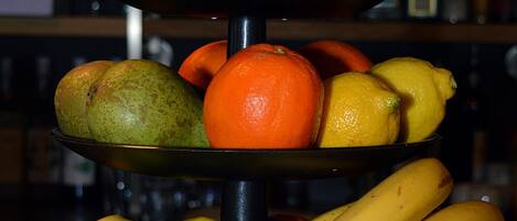 Exhibición de frutas con naranjas, kiwis, manzanas y plátanos.
