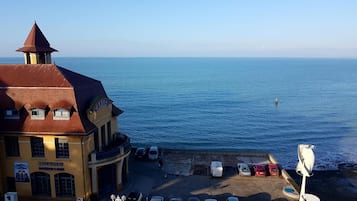 Un bâtiment situé sur la côte, comprenant un casino et un restaurant, un parking avec des voitures, et offrant une vue sur la mer.
