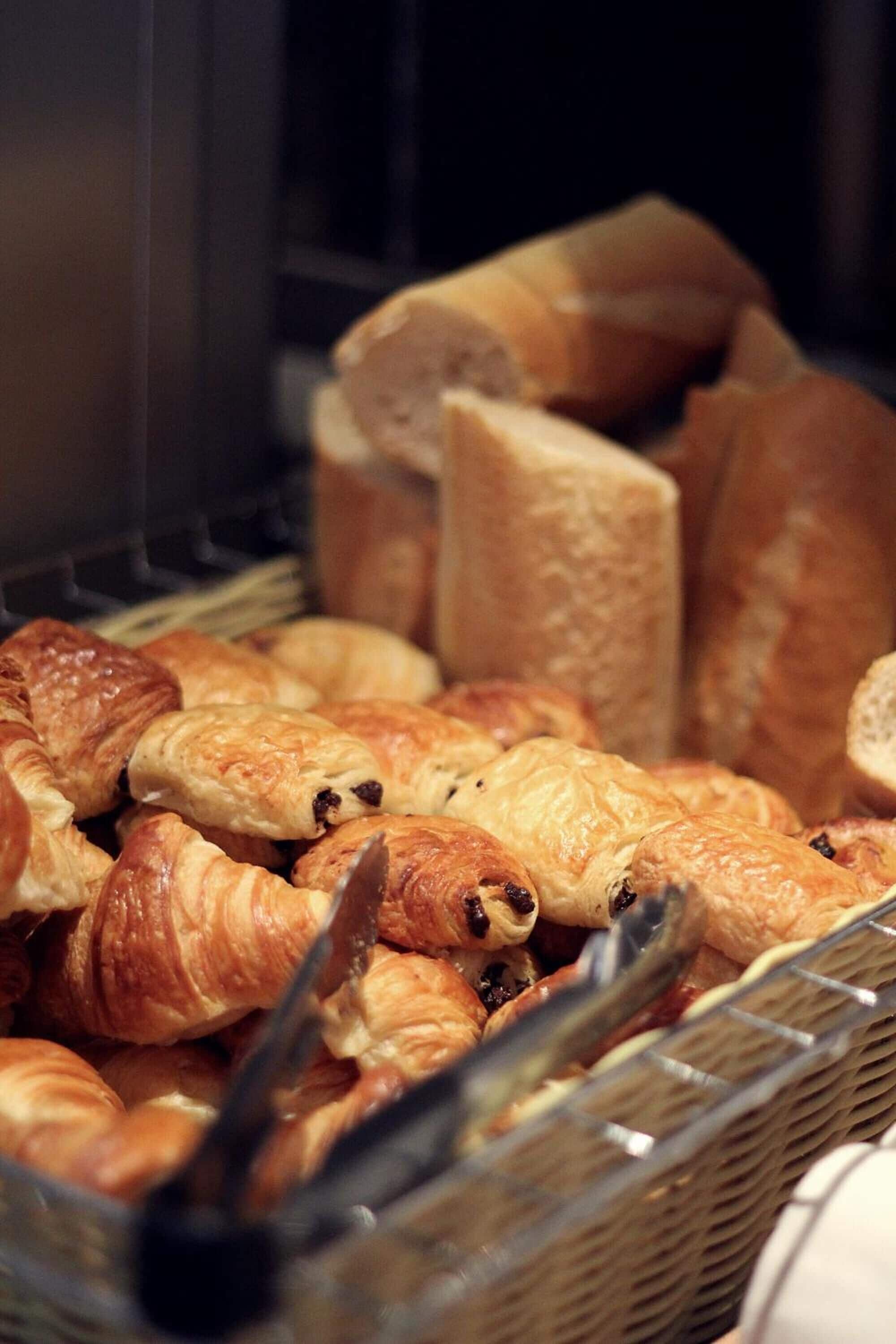 A basket filled with various types of pastries, including croissants and bread rolls.
