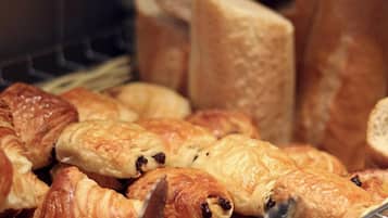 A basket filled with various types of pastries, including croissants and bread rolls.