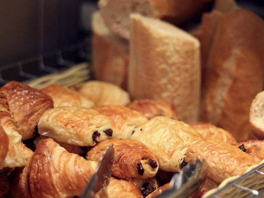 A basket filled with various types of pastries, including croissants and bread rolls.