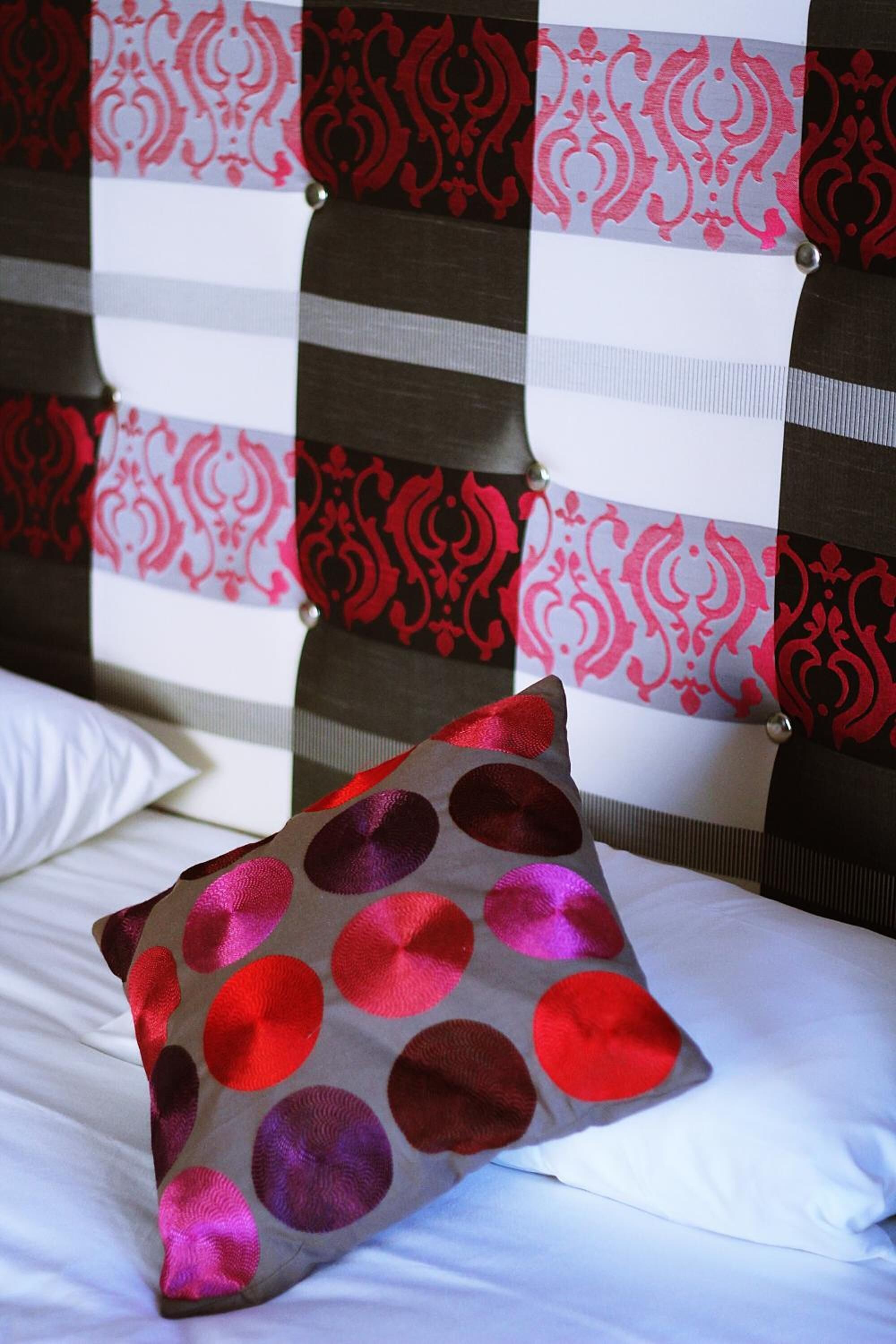 Una cama con un almohadón estampado con lunares.