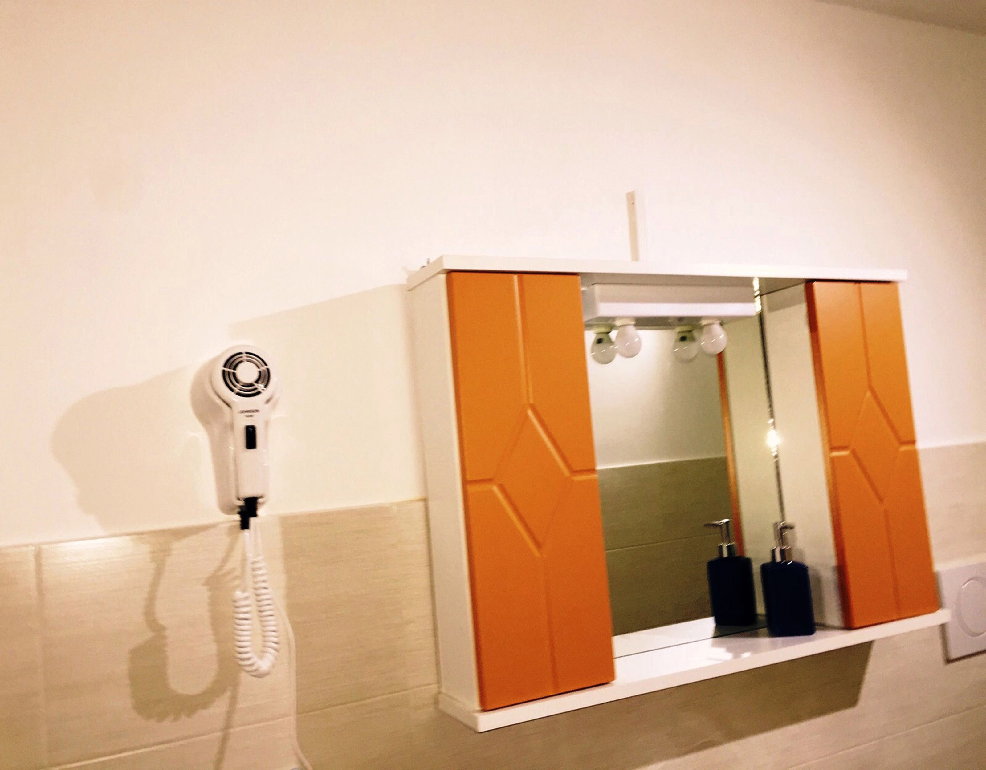 A bathroom with a white wall, a white sink, a mirror, and a towel rack.