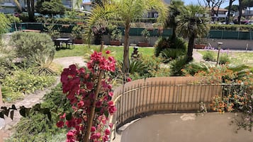 Un jardín con diversas plantas y flores, un muro curvo y un sendero.