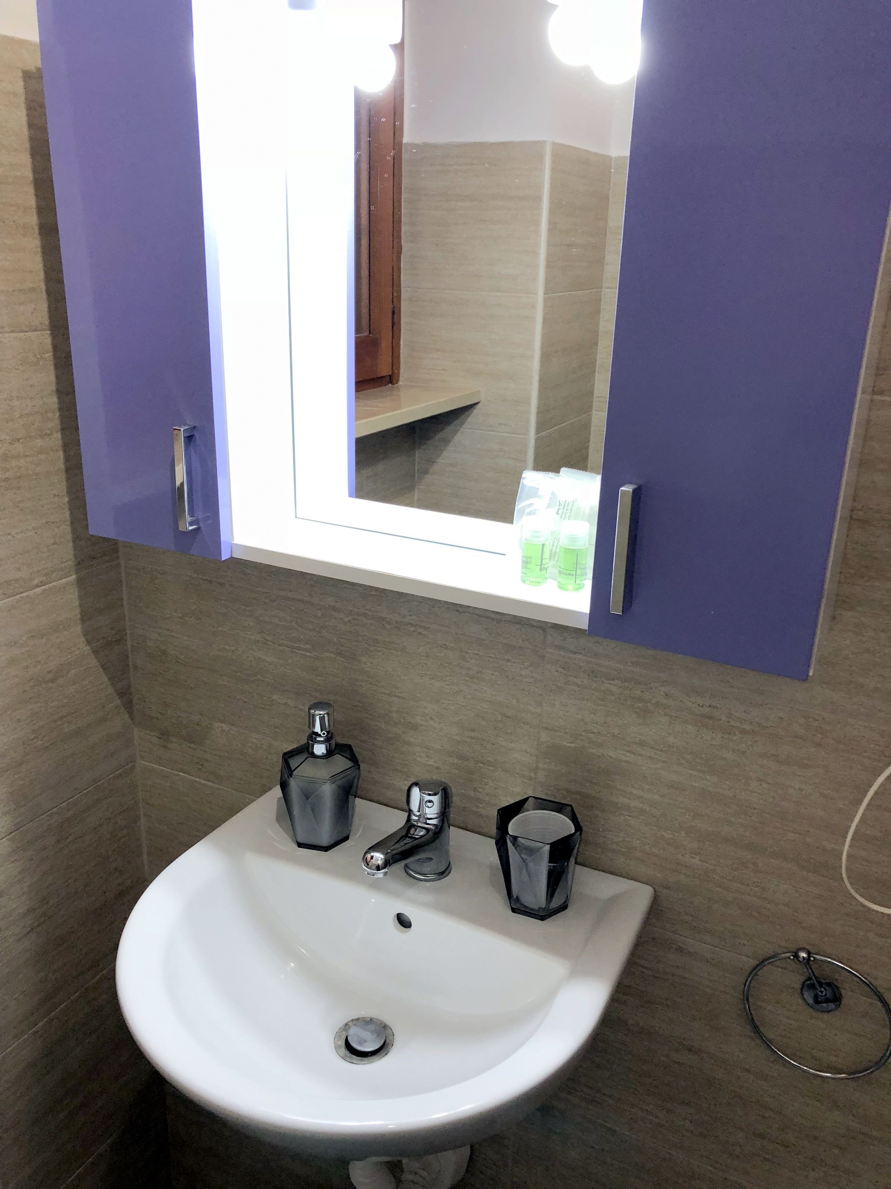 A bathroom with a white sink, a mirror, and a cabinet above it.