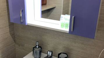 A bathroom with a white sink, a mirror, and a cabinet above it.