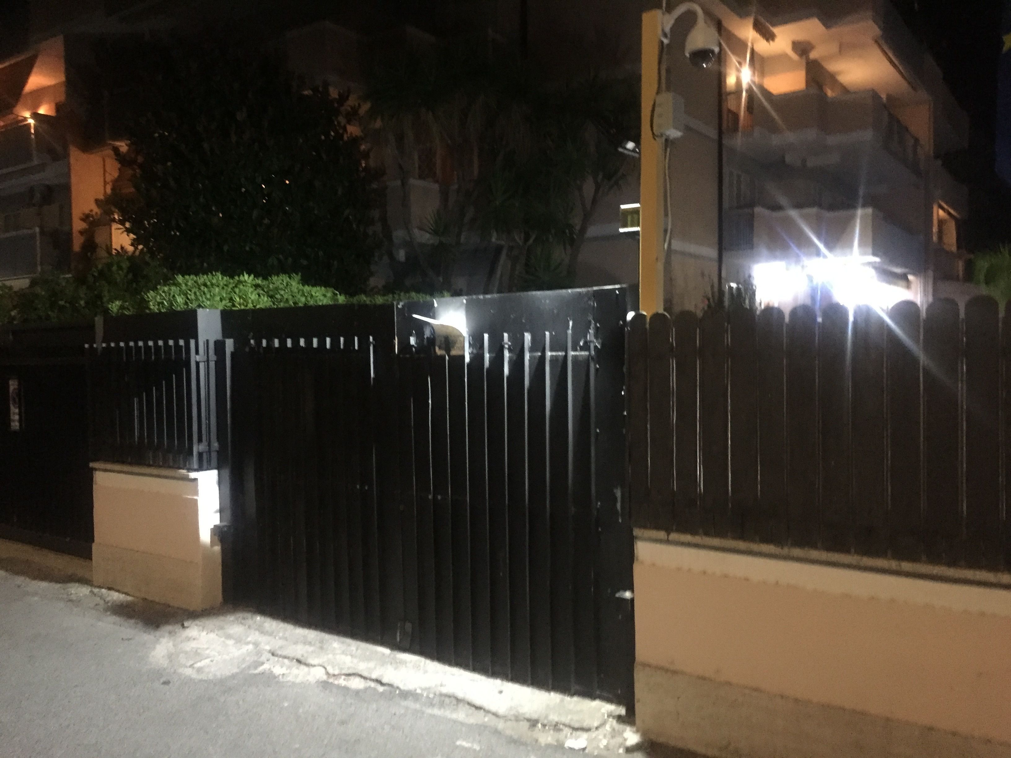 Ein durch eine schwarze Zäunung abgegrenztes Grundstück mit Betonfundament und einer Straßenlaterne.