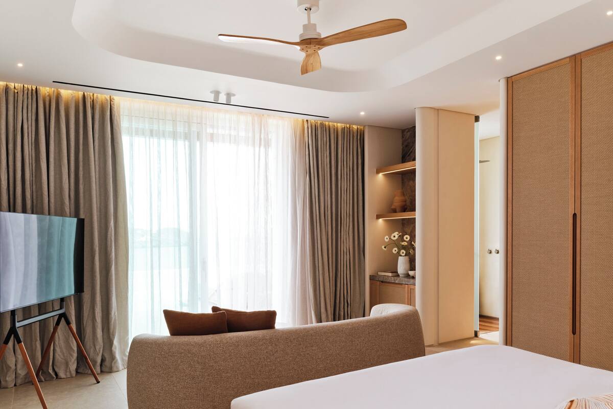 Una habitación de hotel moderna con una cama grande, una zona de estar, un televisor de pantalla plana y un armario.