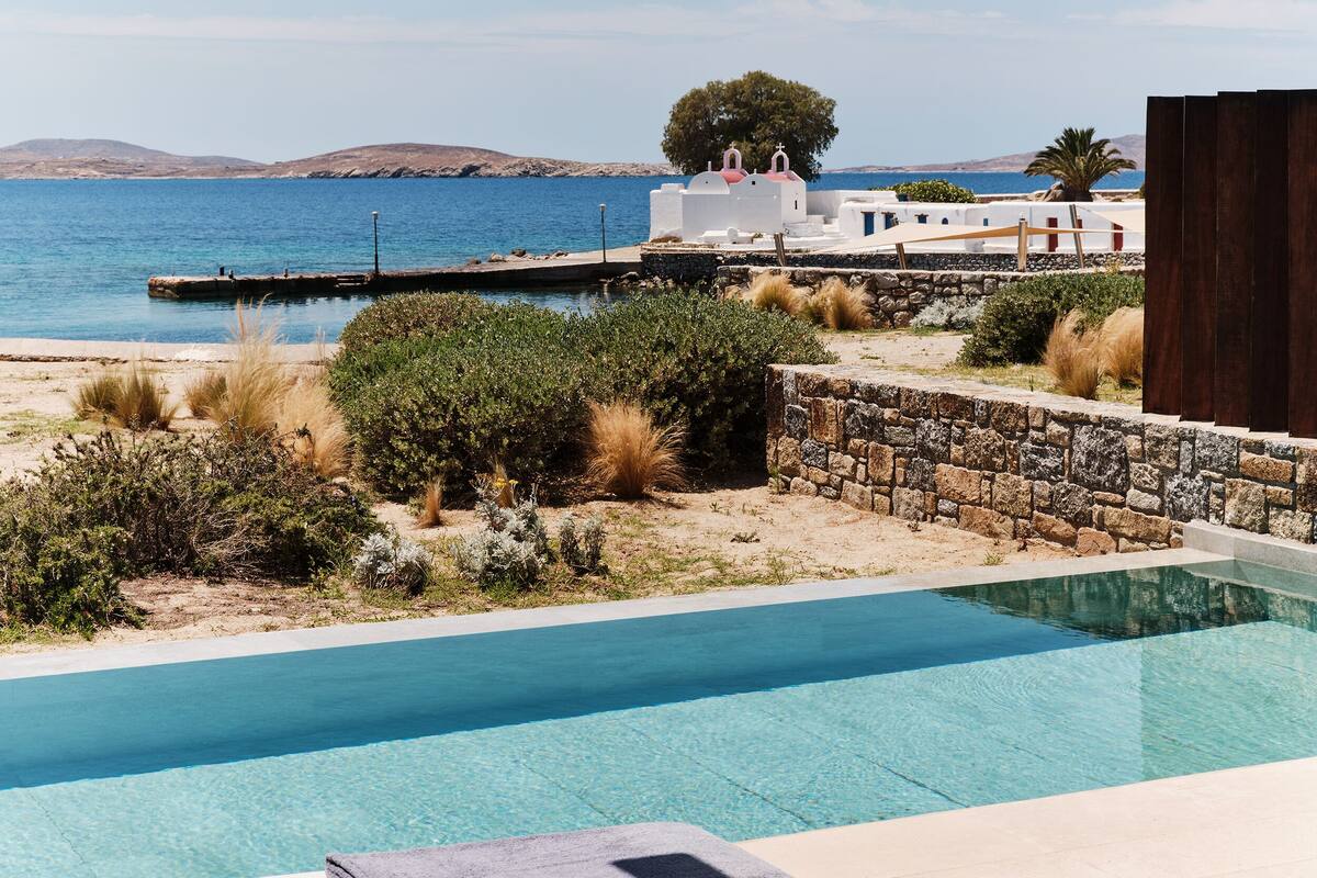 Un área junto a la piscina con sillones de descanso y vista al mar.