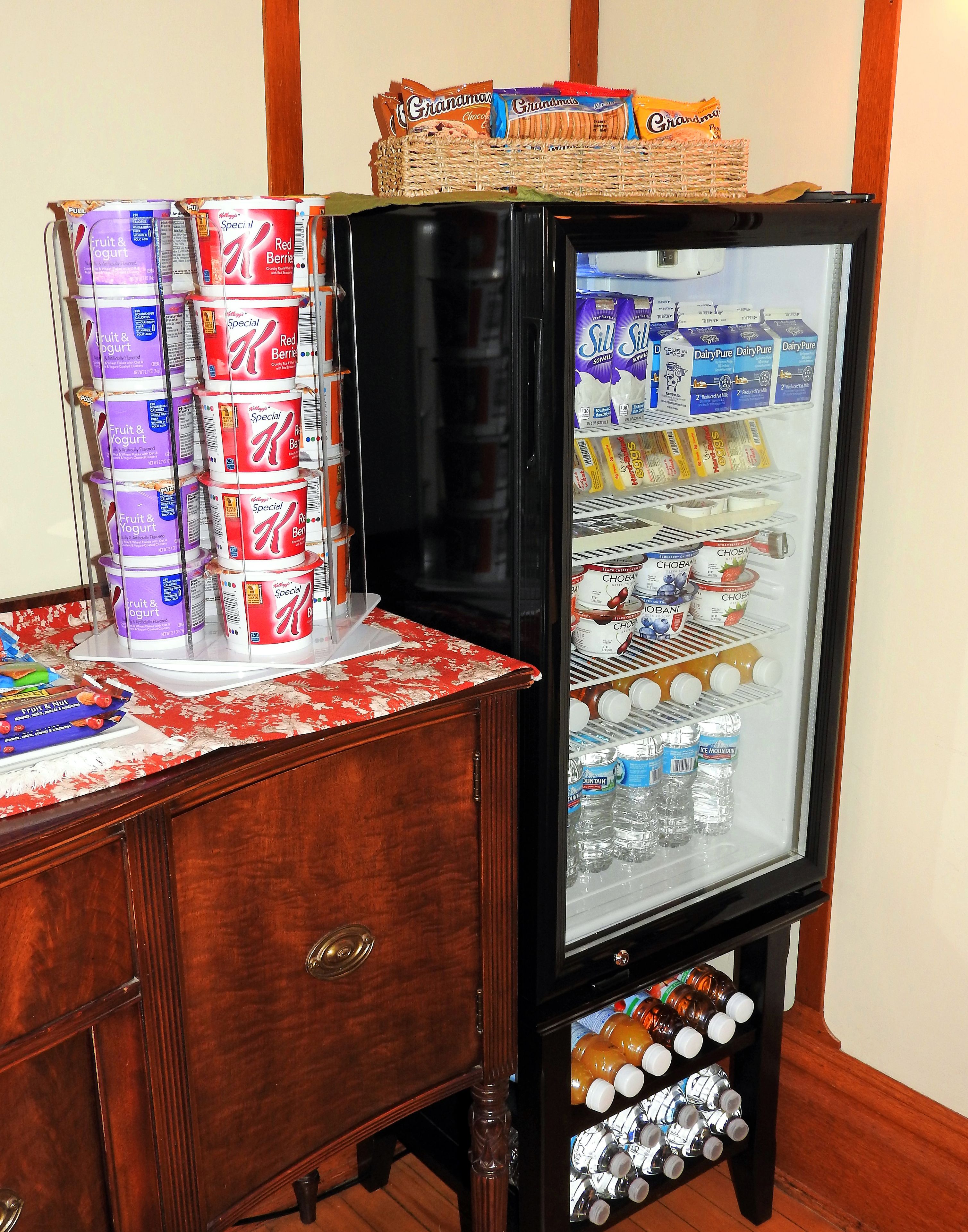 Un refrigerador lleno de diversos alimentos y bebidas, como lácteos, fruta y yogur, además de botellas de agua.