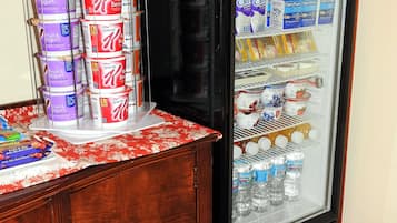 Un refrigerador lleno de diversos alimentos y bebidas, como lácteos, fruta y yogur, además de botellas de agua.