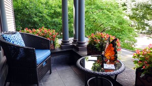 A balcony with wicker furniture, a glass table, and potted plants.