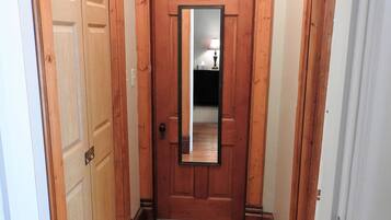 A hallway with wooden flooring and a wooden door with a mirror.