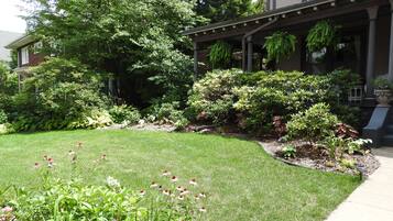 Un jardín bien cuidado con diversas plantas y flores frente a una casa.