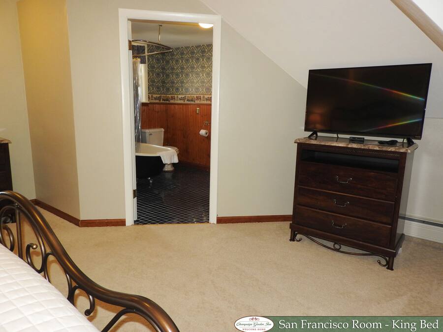 Ein Zimmer mit einem Kingsize-Bett, einem Fernseher auf einer Kommode und einem durchgegangenen Tür erkennbaren Badezimmer.