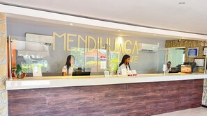 A reception desk with a glass partition and the name 'MENDILUNA' in large letters. - Hotel Mendihuaca by On Vacation (Santa Marta)