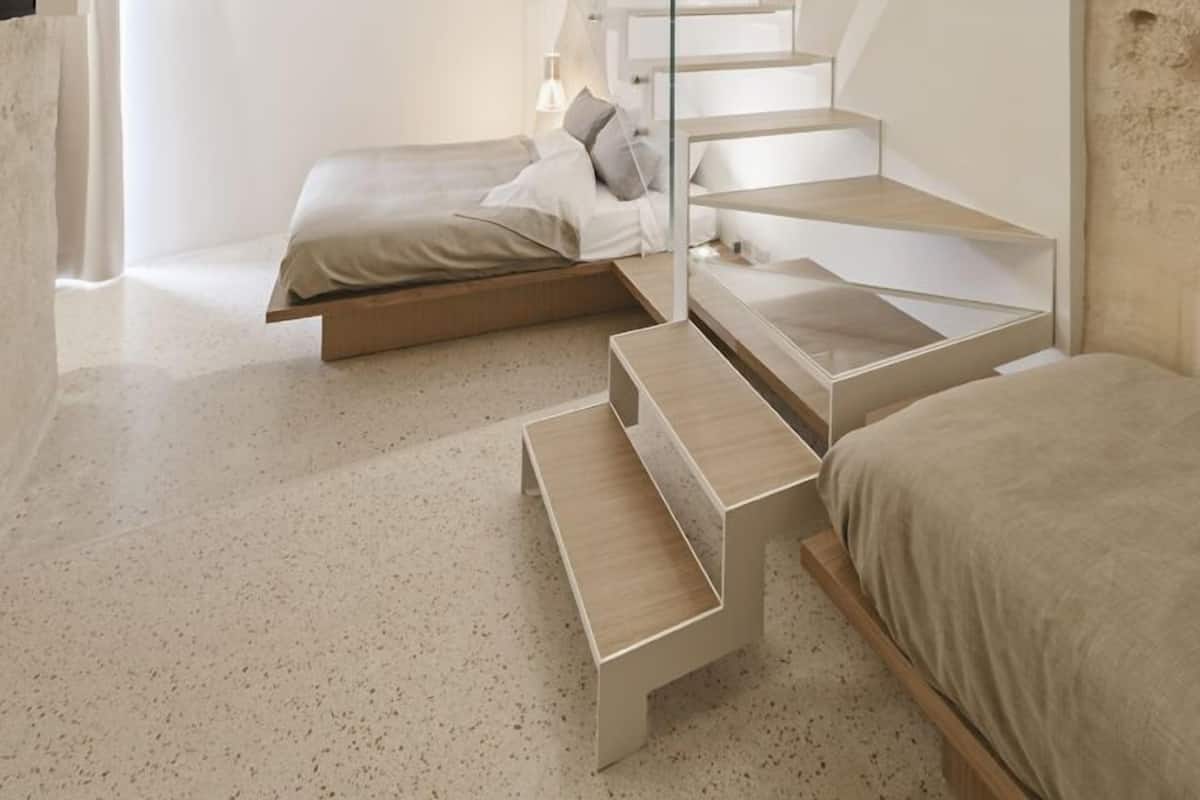 A modern bedroom with a unique arched ceiling, a minimalist staircase, and a bed with a wooden platform.