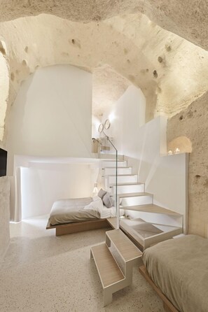 A modern bedroom with a unique arched ceiling, a minimalist staircase, and a bed with a wooden platform. - La Dimora di Metello (Matera)