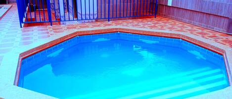 En swimmingpool med blå fliseterrasse og et skilt, der angiver røgfri zone.