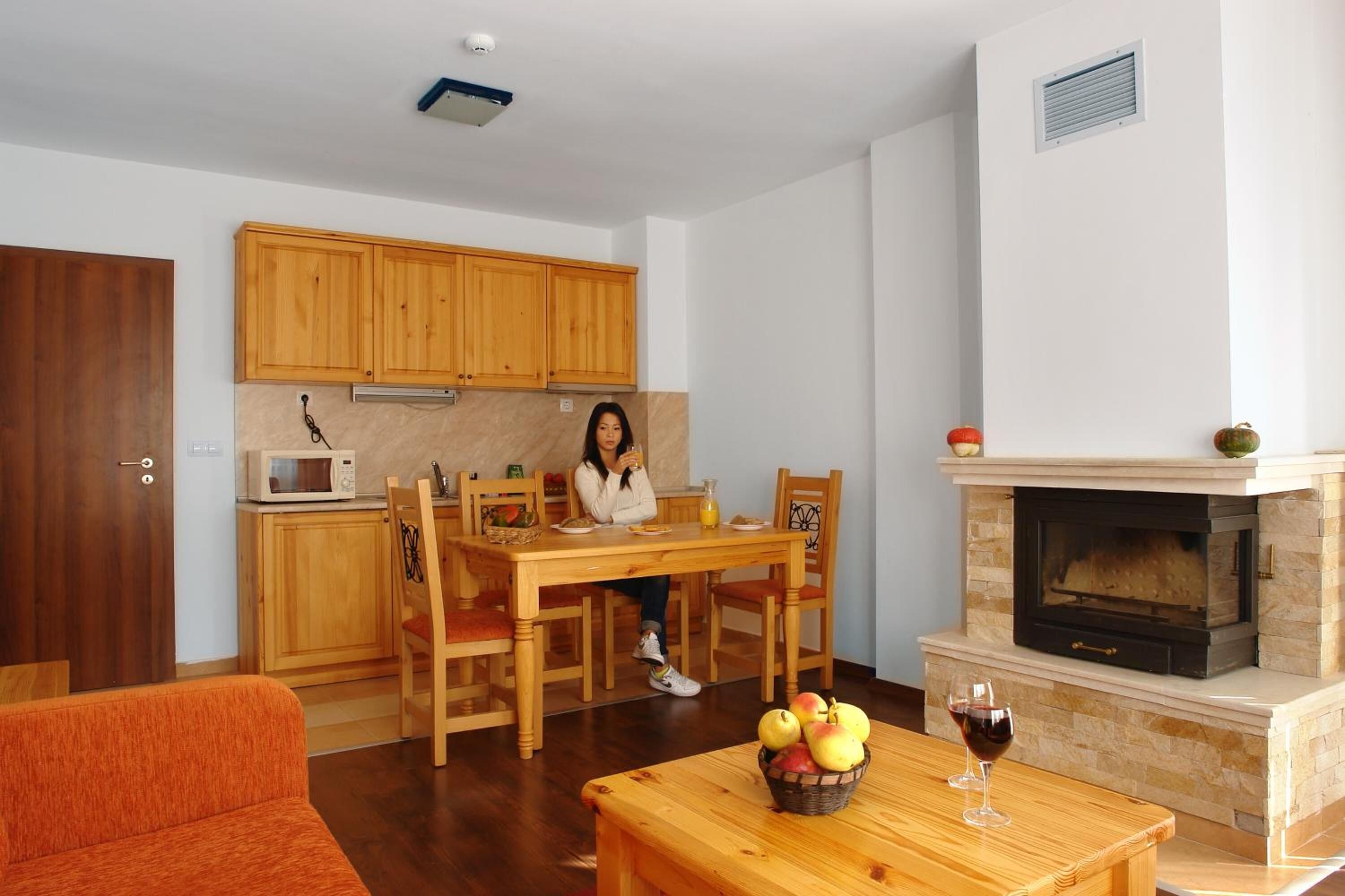 Un salon chaleureux comprenant un coin repas, une cheminée et des meubles de rangement en bois.
